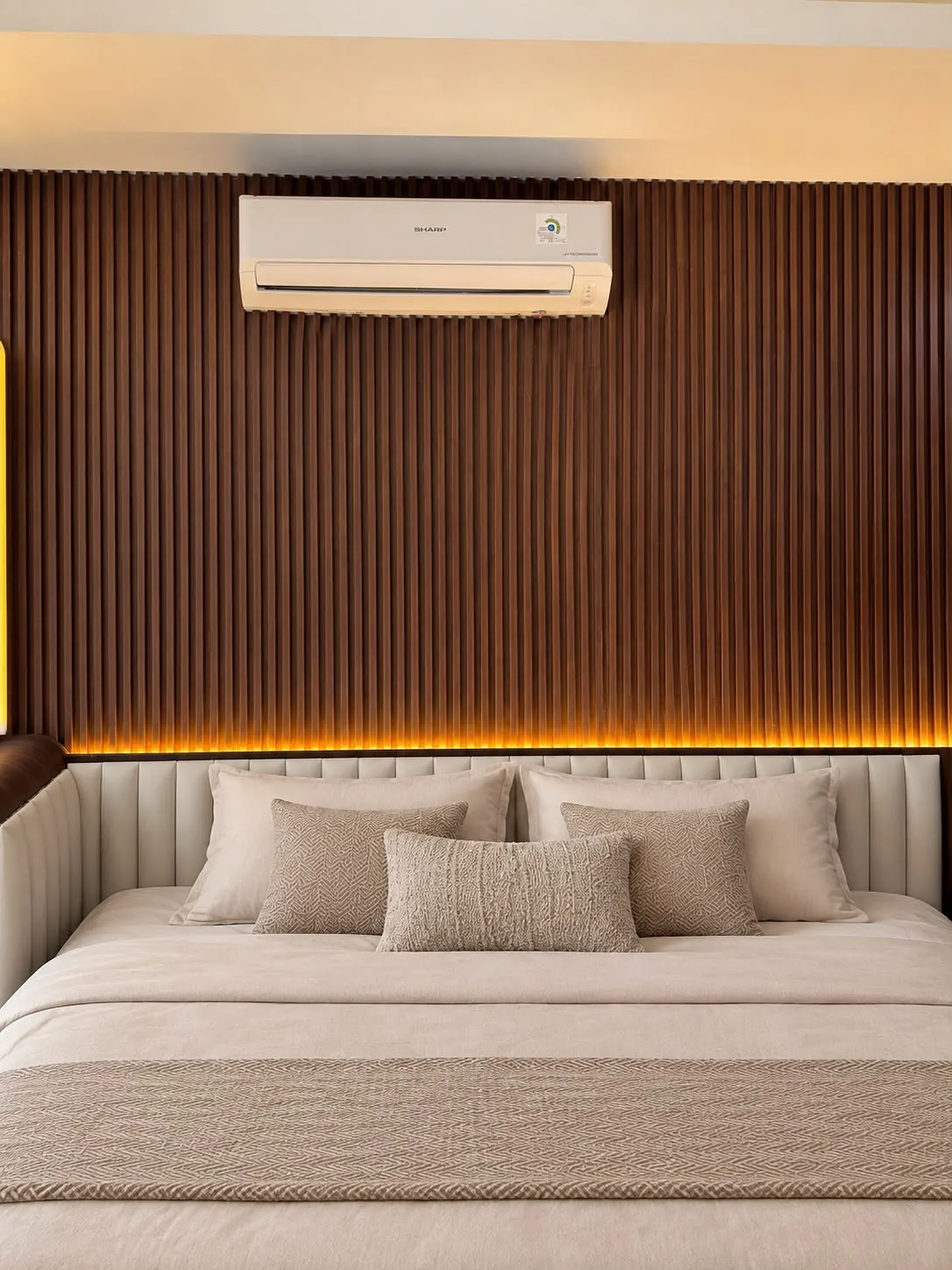 Detail panel beralur, cahaya hangat, dan kepala tempat tidur berlapis kain.
